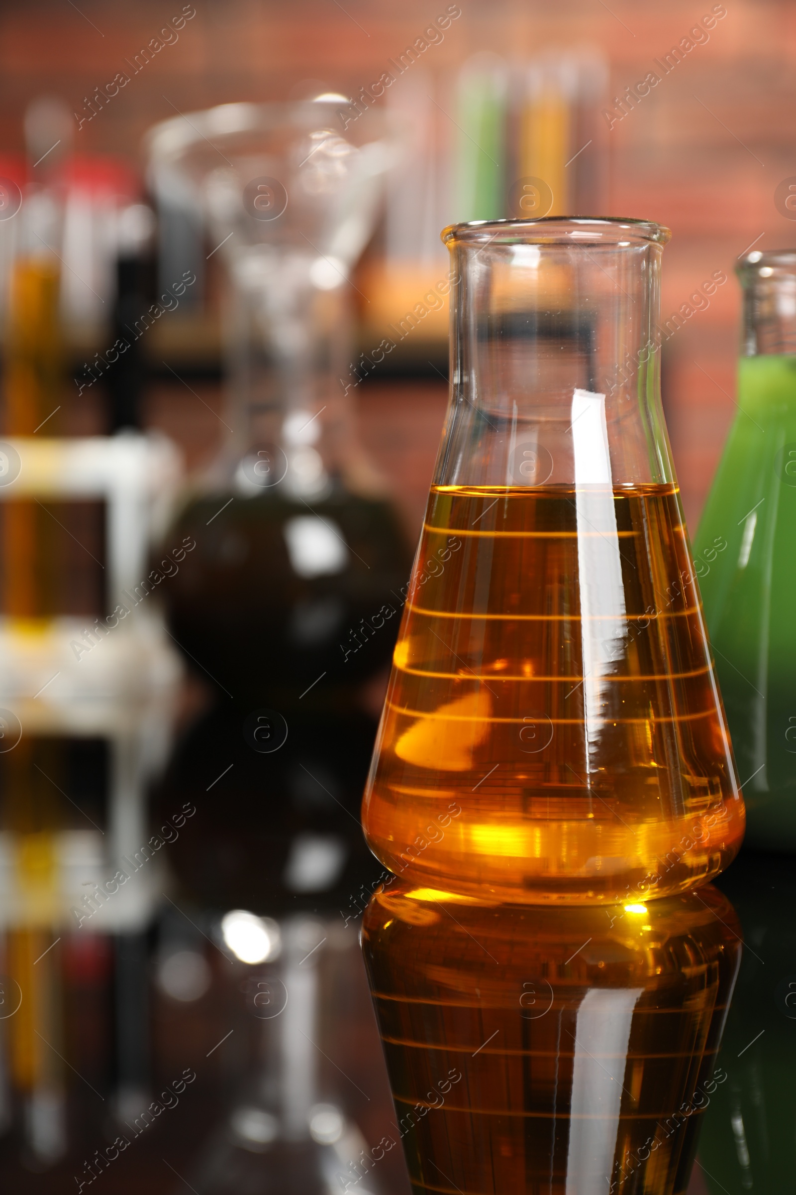 Photo of Laboratory glassware with different types of oil on mirror table, closeup