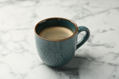 Photo of Tasty coffee in cup on white marble table, closeup