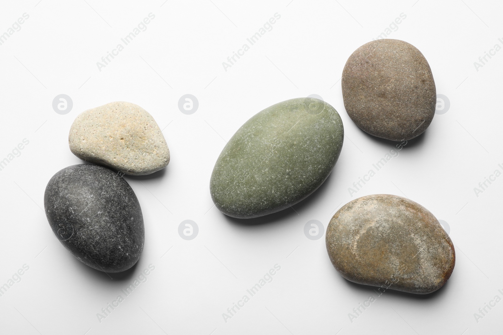 Photo of Many different stones on white background, top view