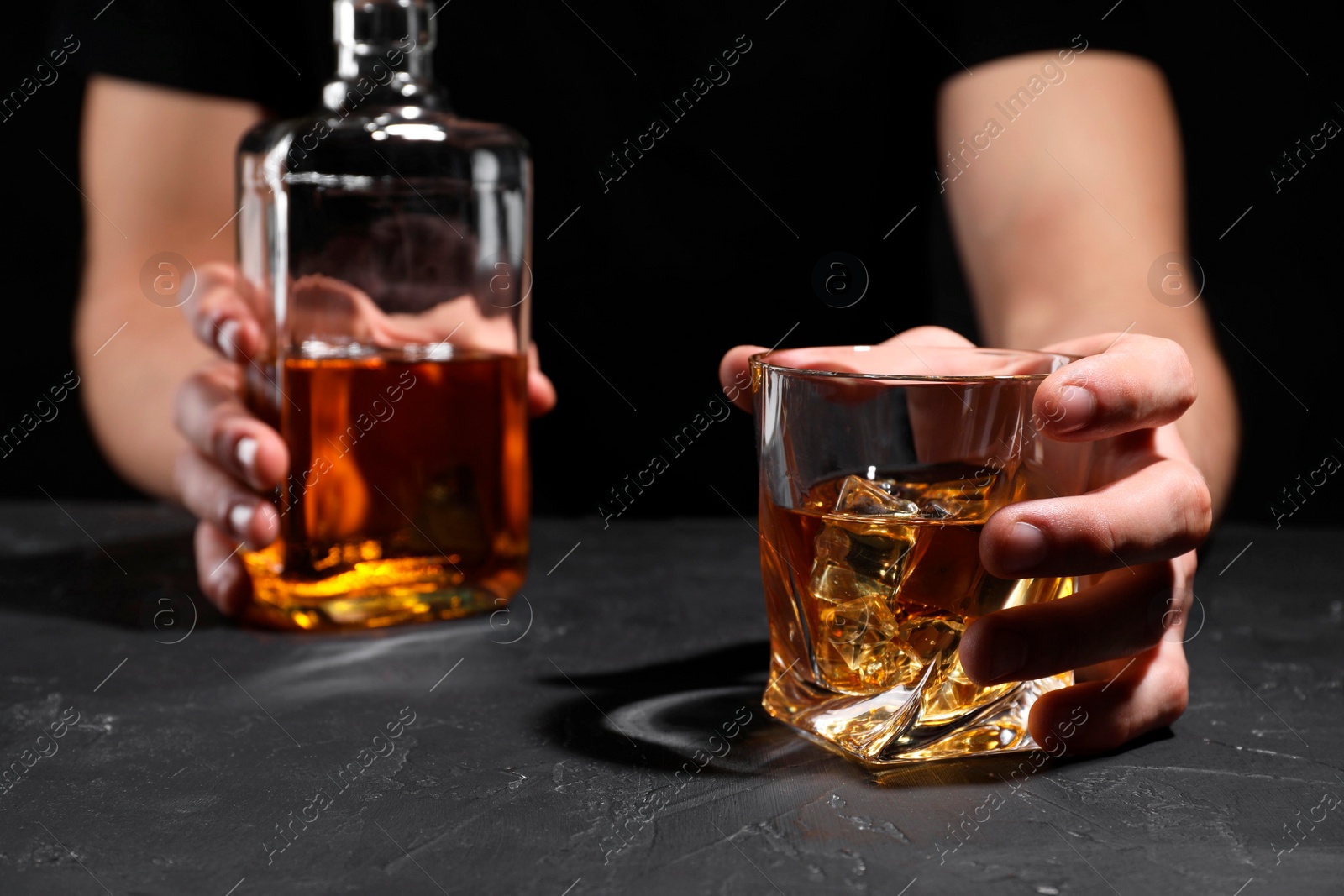 Photo of Alcohol addiction. Man with whiskey at dark textured table, selective focus