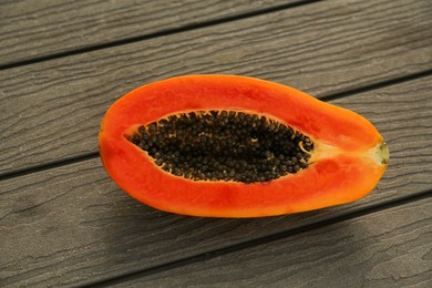 Photo of Half of fresh ripe papaya fruit on wooden table, top view