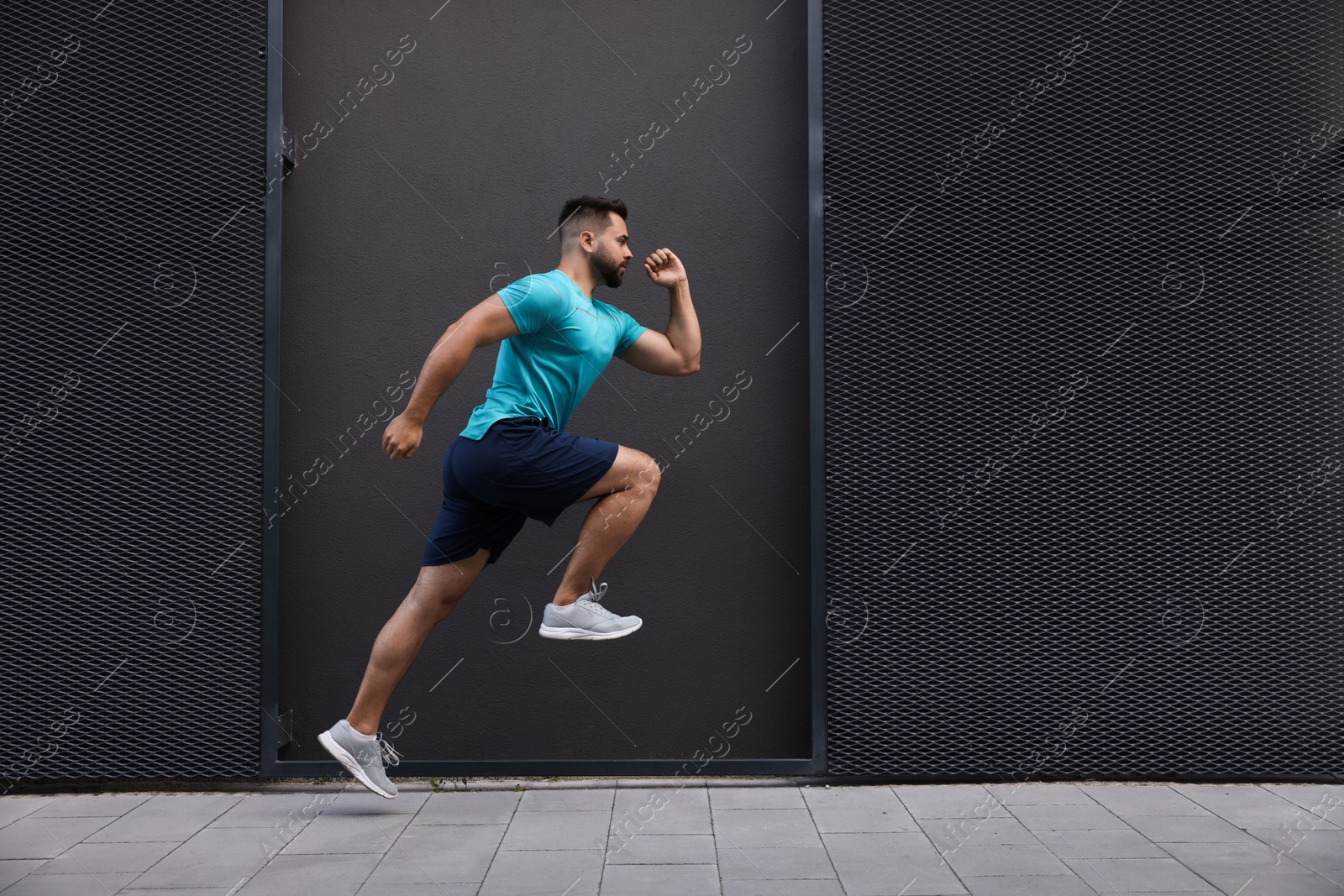 Photo of Young man running near building outdoors. Space for text