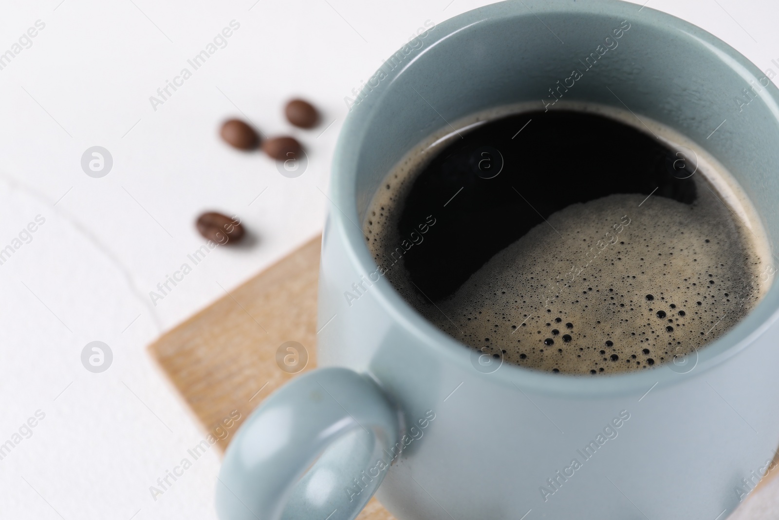 Photo of Delicious coffee in cup on white table, closeup. Space for text