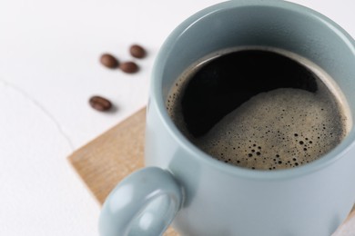 Delicious coffee in cup on white table, closeup. Space for text