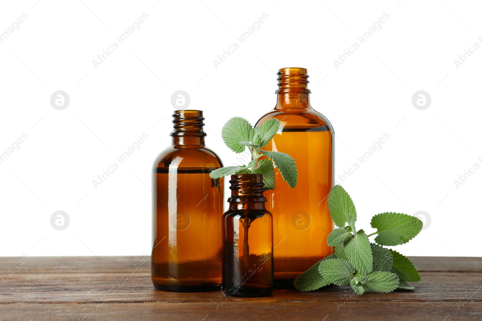 Photo of Bottles of essential oil and mint on wooden table against white background