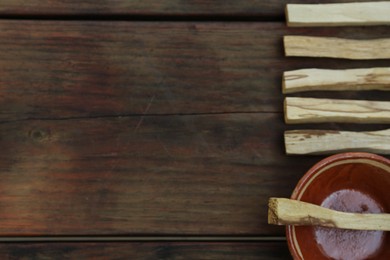 Palo santo sticks and bowl on wooden table, flat lay, Space for text