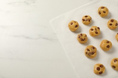 Photo of Unbaked chocolate chip cookies on white marble table, flat lay. Space for text