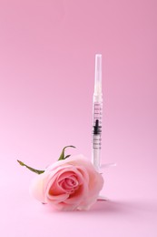 Photo of Cosmetology. Medical syringe and rose flower on pink background