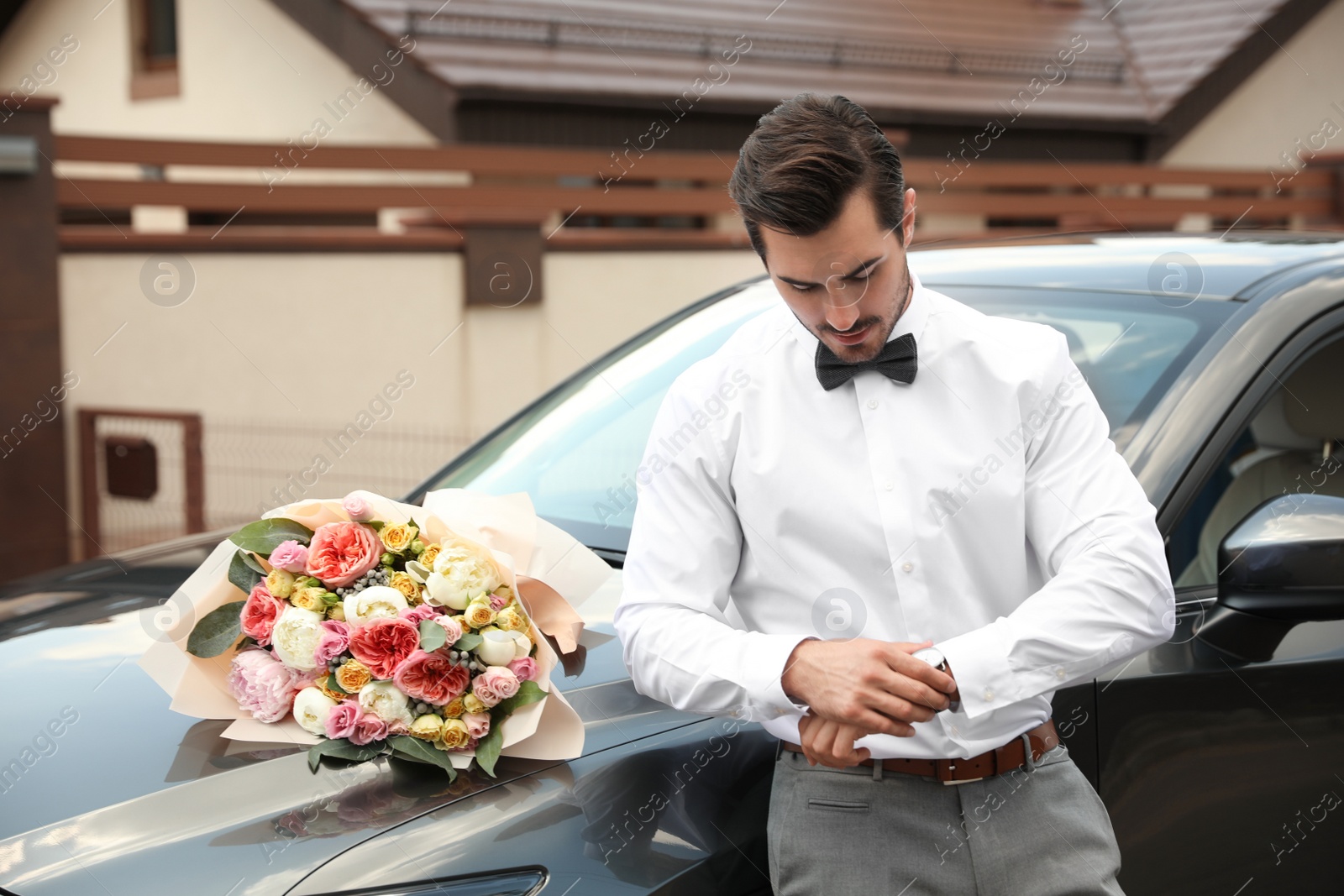 Photo of Young handsome man with beautiful flower bouquet near car outdoors