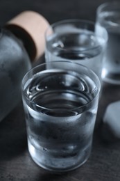 Shot glasses of vodka with ice on dark table, closeup