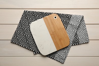 Kitchen towel and cutting board on white wooden table, top view