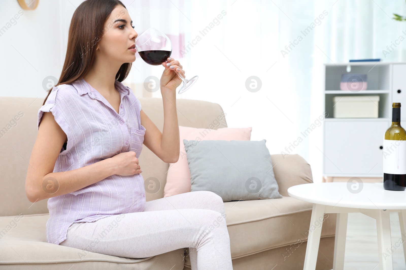 Photo of Future mother drinking wine from glass at home. Alcohol abuse during pregnancy