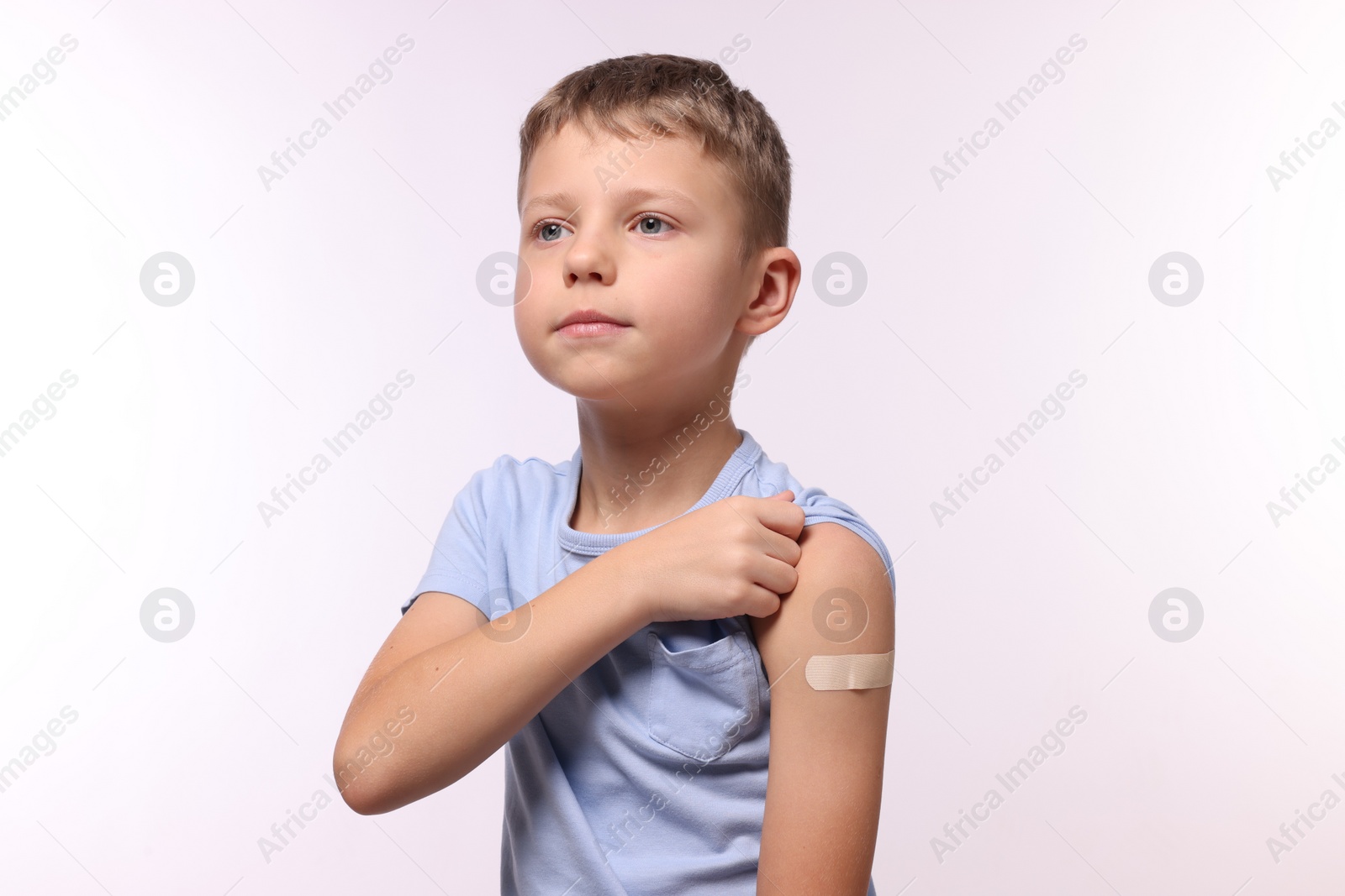 Photo of Boy with sticking plaster on arm after vaccination against white background