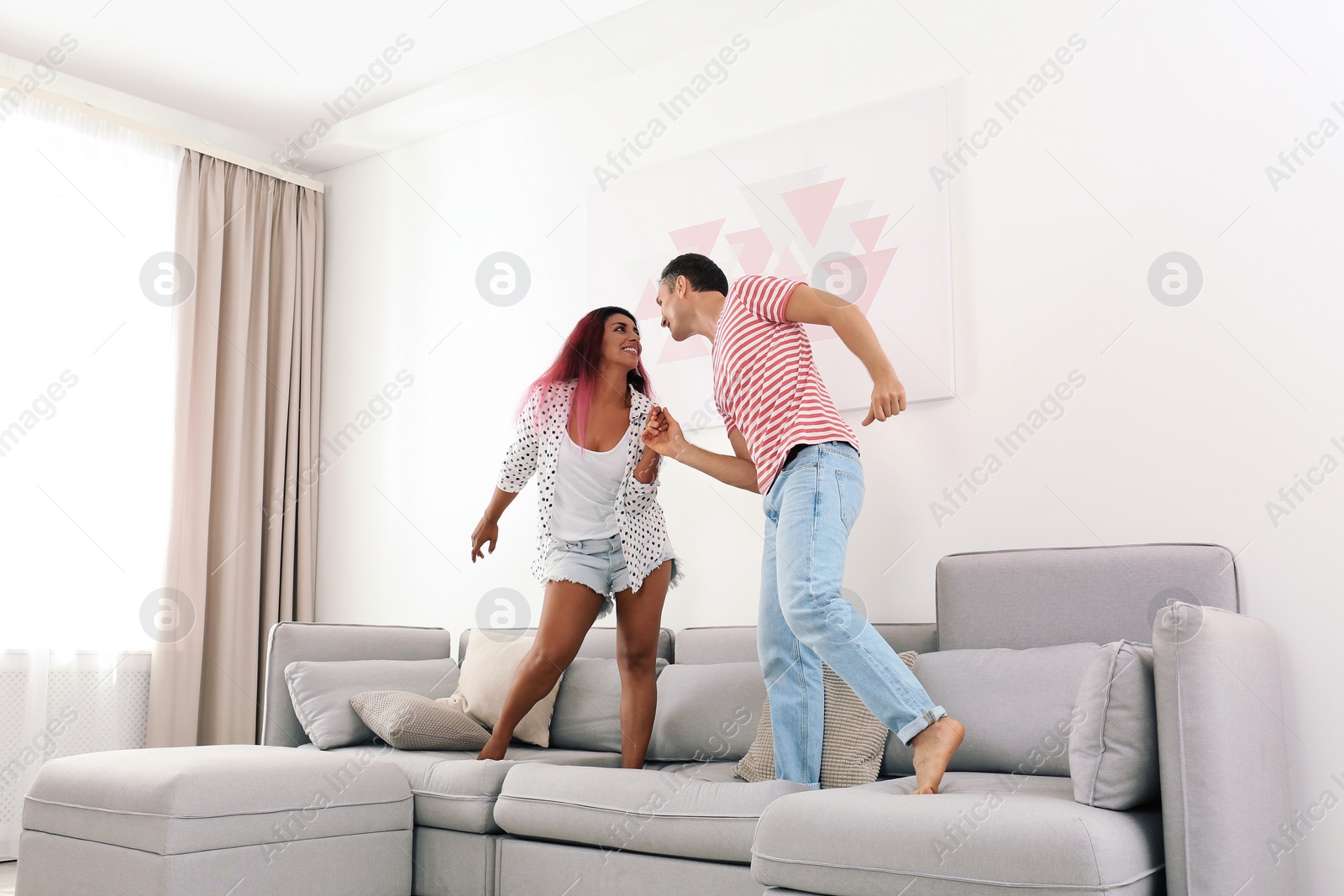 Photo of Beautiful happy couple dancing on sofa at home