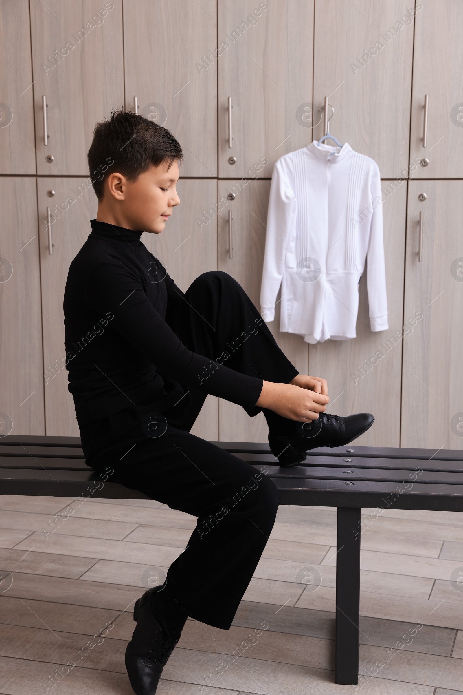 Photo of Little boy putting on shoes in locker room