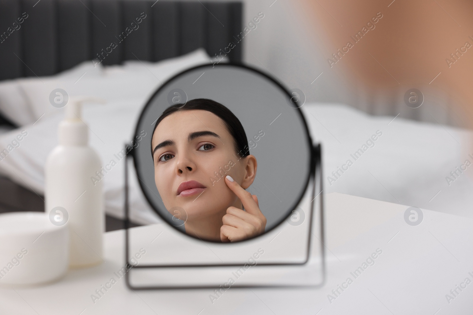 Photo of Woman with dry skin looking at mirror indoors