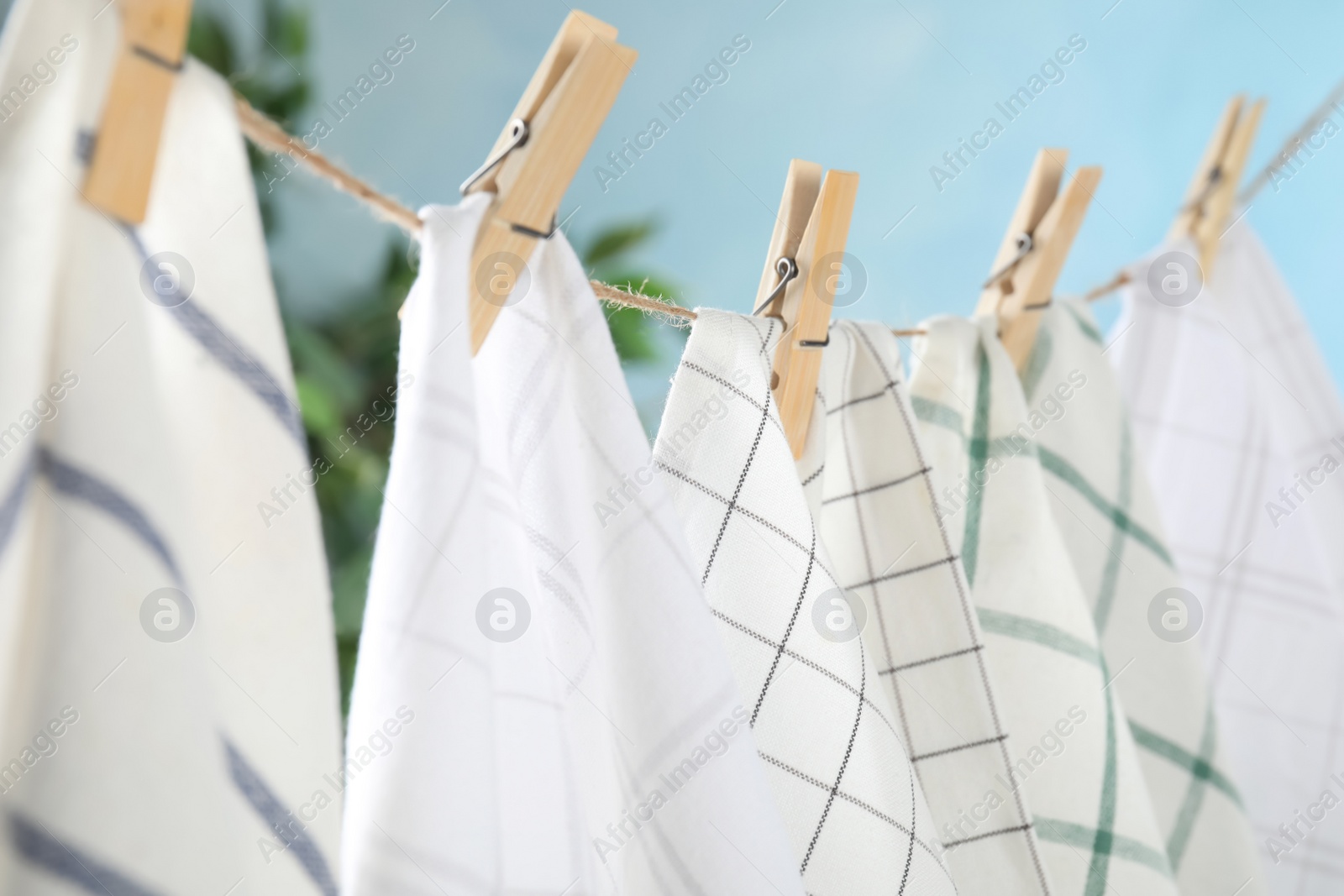 Photo of Washing line with wooden clothespins and fabrics against blurred background