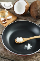 Photo of Frying pan with organic coconut cooking oil and spoon on wooden table