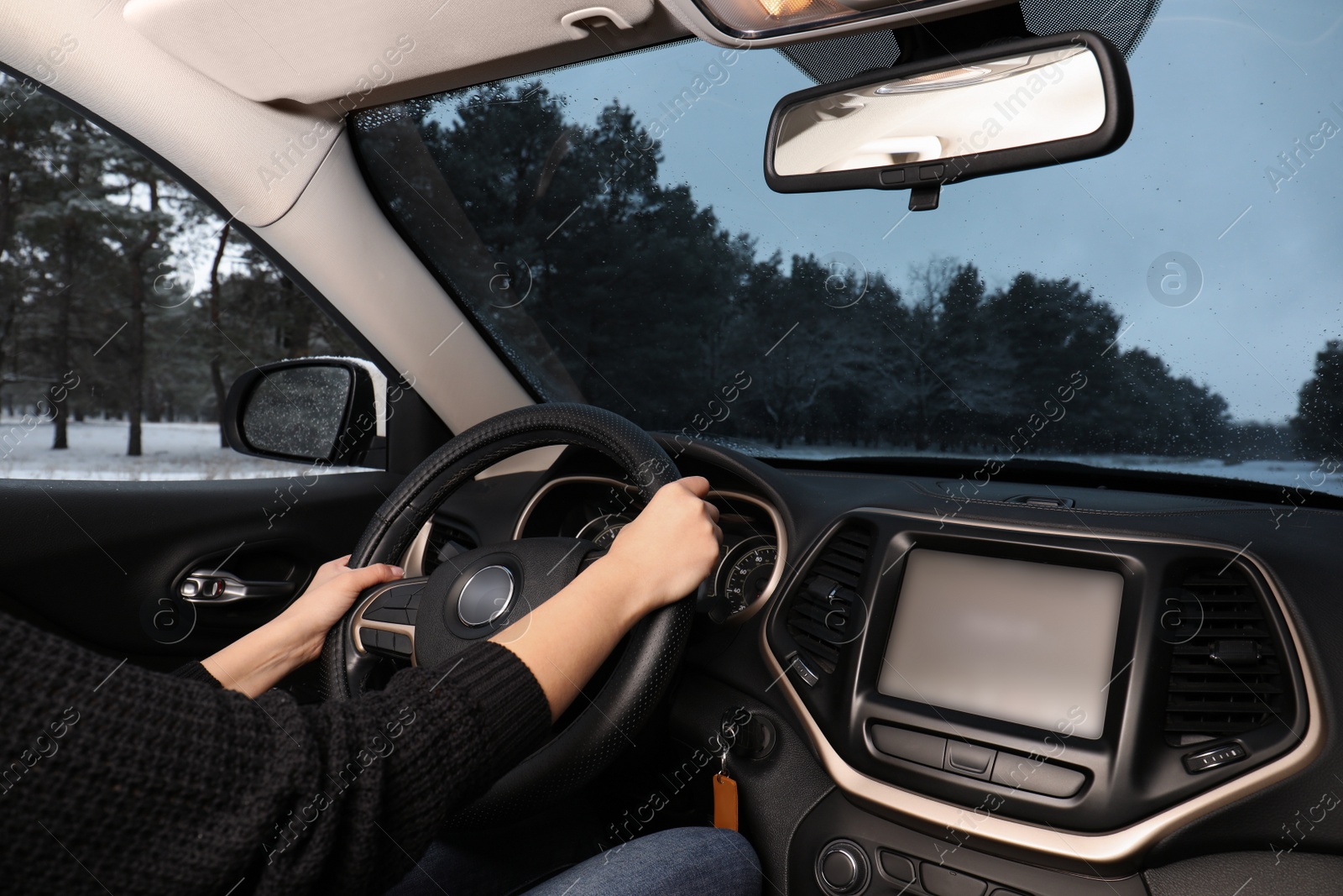 Photo of Young woman driving car along winter forest, closeup