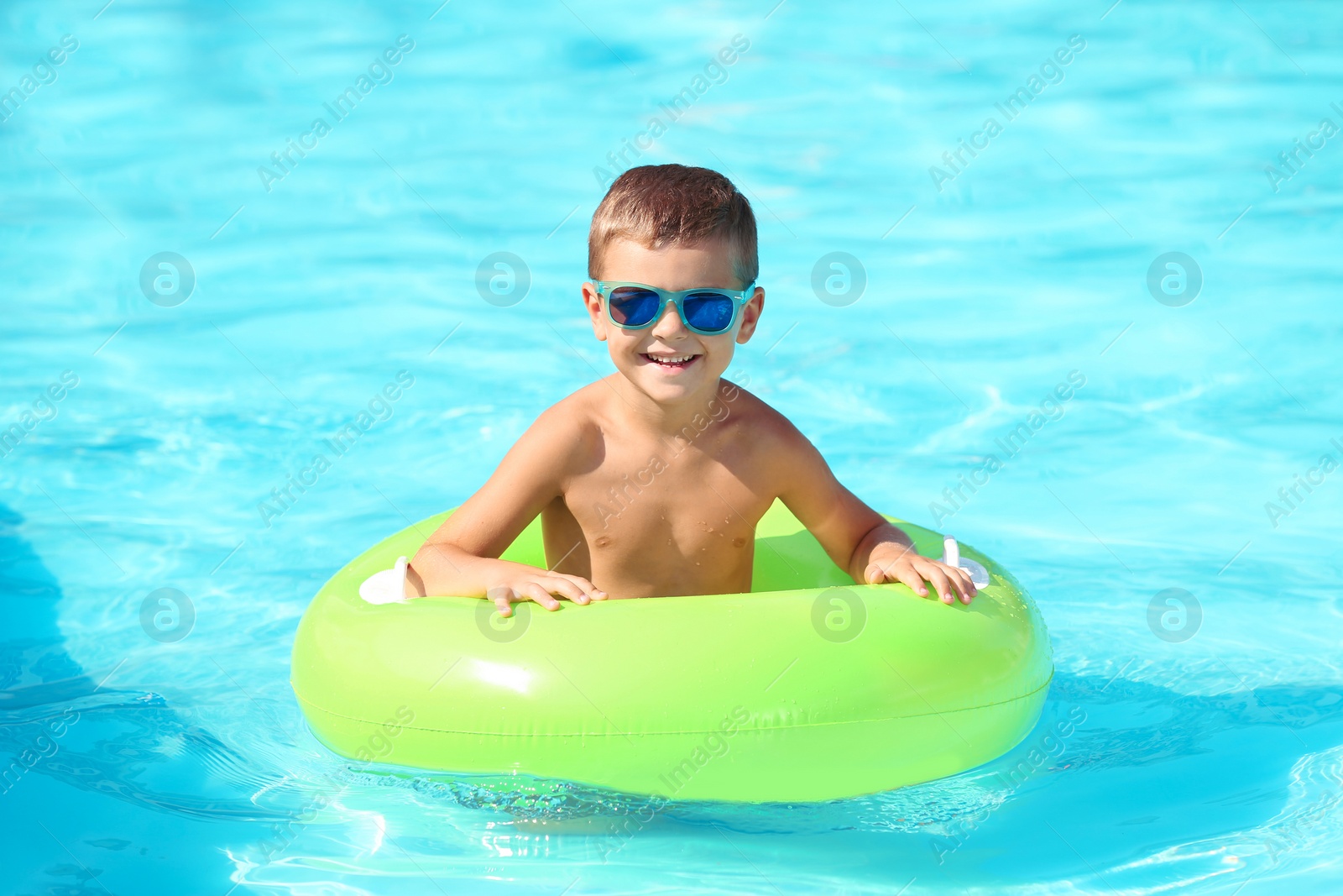 Photo of Happy little boy with inflatable ring in swimming pool