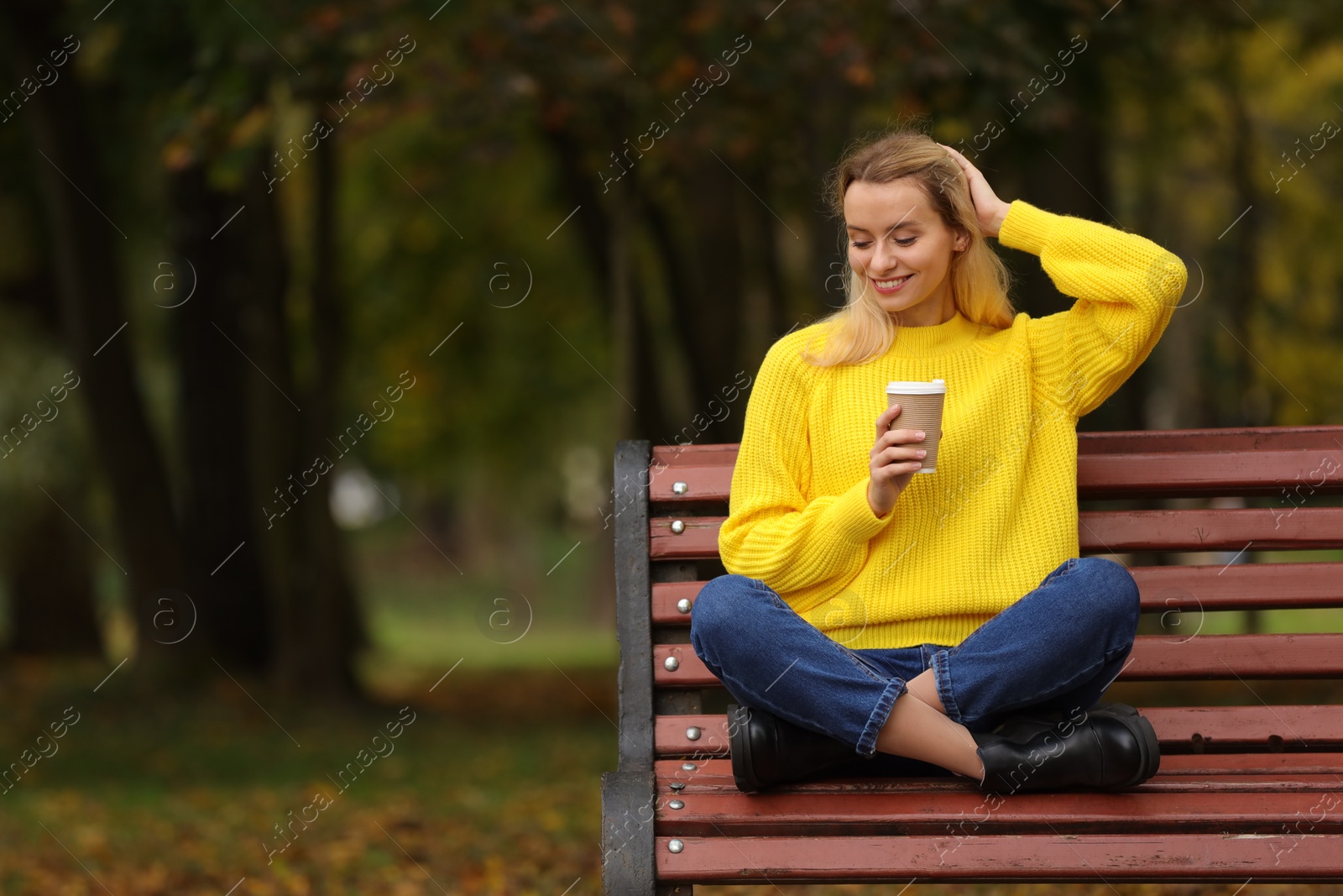 Photo of Happy woman with paper cup in autumn park. Space for text