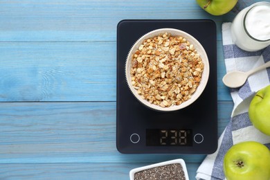 Photo of Electronic scales with granola and different products on light blue wooden table, flat lay. Space for text