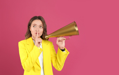 Young woman with megaphone on pink background