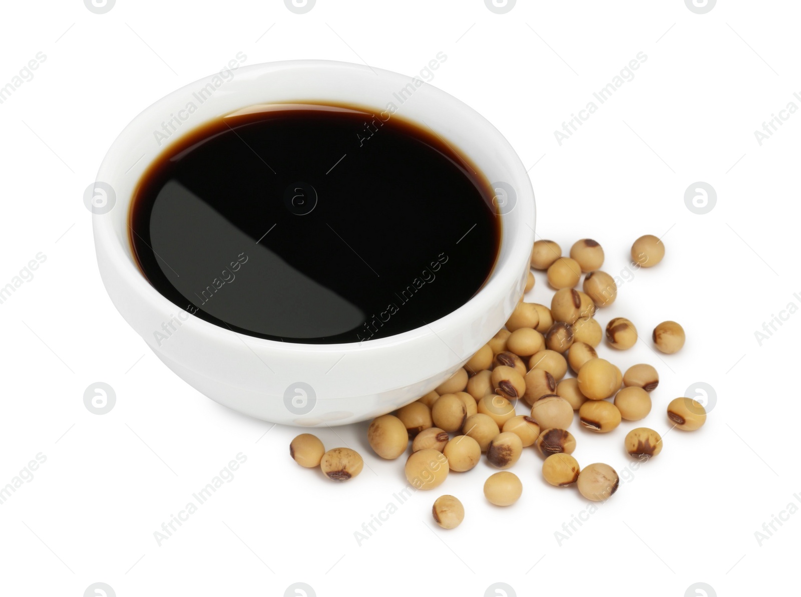 Photo of Tasty soy sauce in bowl and soybeans isolated on white