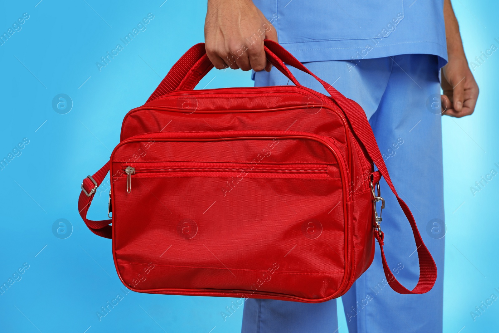 Photo of Male doctor with first aid kit on color background, closeup. Medical object