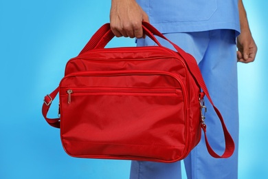 Photo of Male doctor with first aid kit on color background, closeup. Medical object