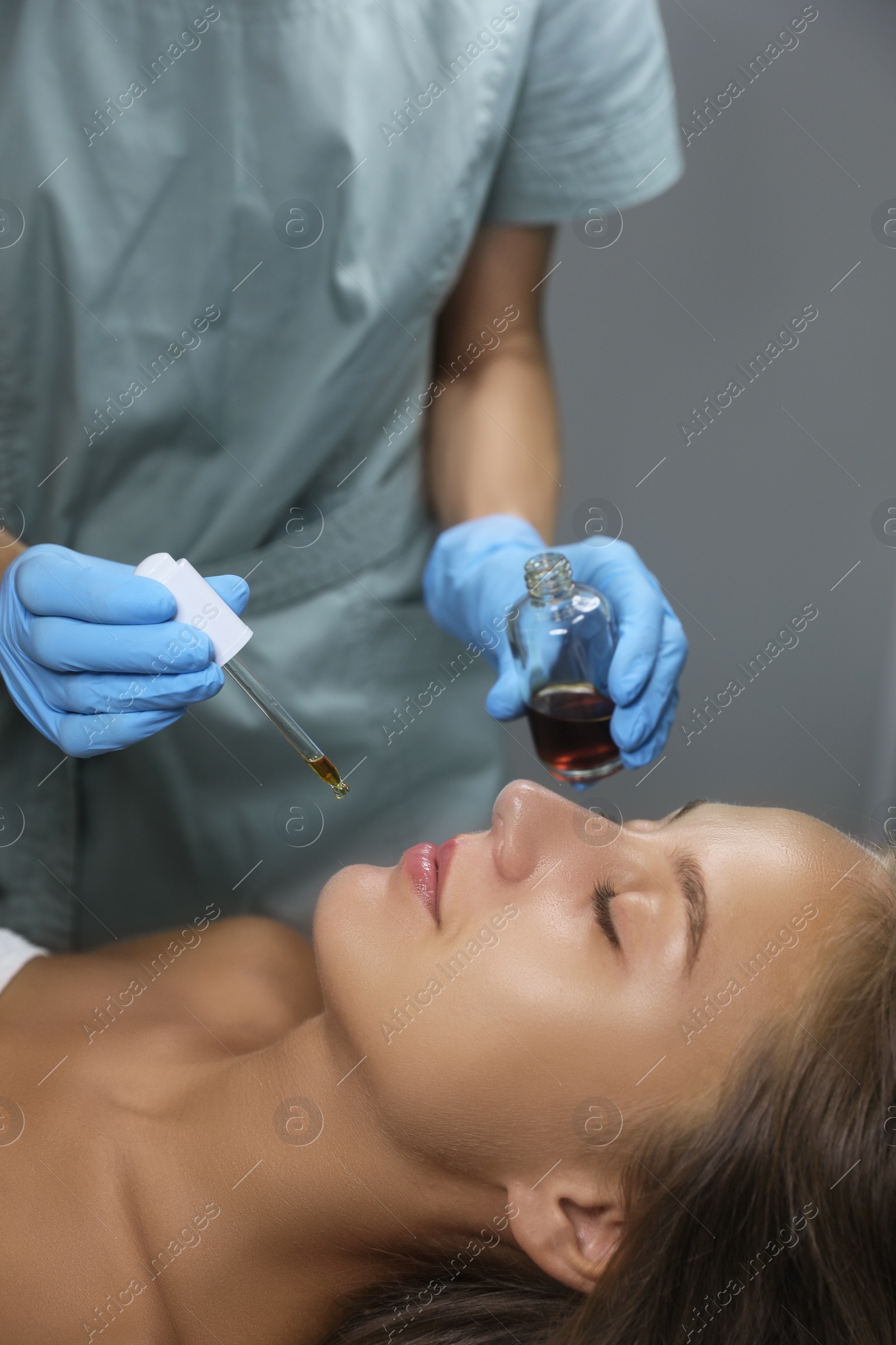 Photo of Cosmetologist applying serum on client's face in salon