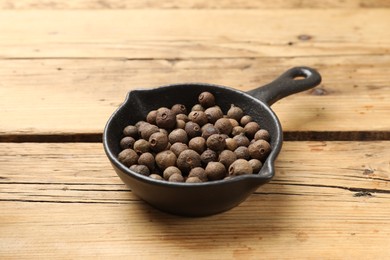 Photo of Dry allspice berries (Jamaica pepper) in dish on wooden table