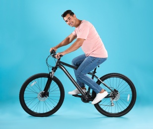 Photo of Handsome young man with modern bicycle on light blue background