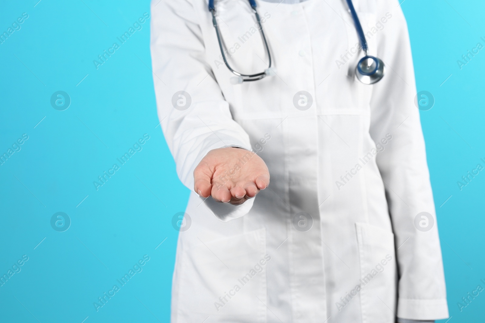 Photo of Female doctor offering helping hand on color background, closeup