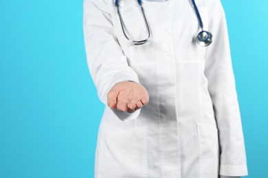 Female doctor offering helping hand on color background, closeup