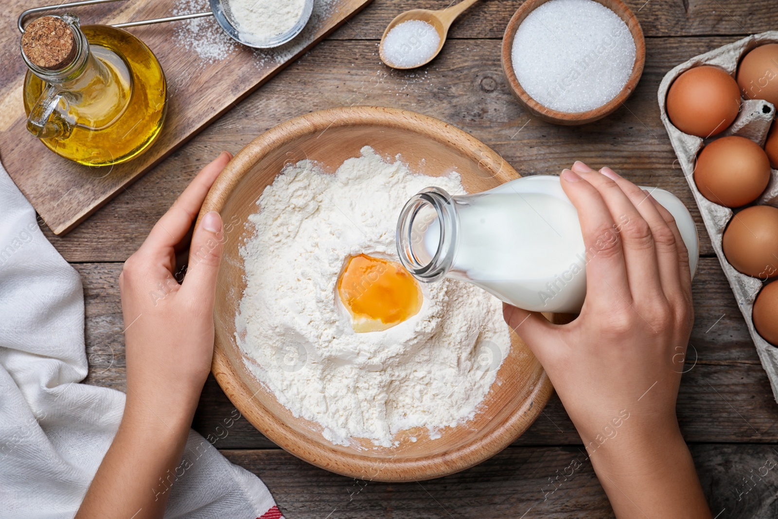 Photo of Woman preparing batter for thin pancakes at wooden table, top view