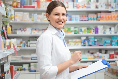 Professional pharmacist with clipboard in modern drugstore