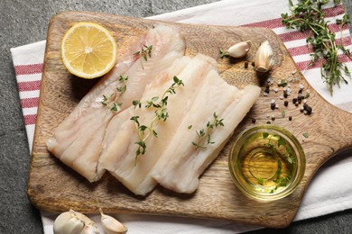 Raw cod fish, microgreens, lemon, spices and oil on grey textured table, top view