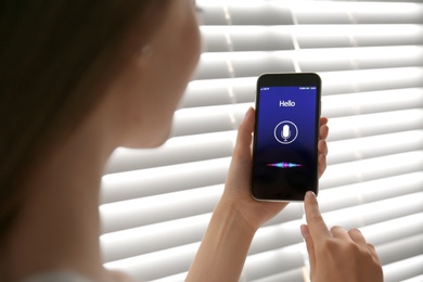 Woman using voice search on smartphone indoors, closeup