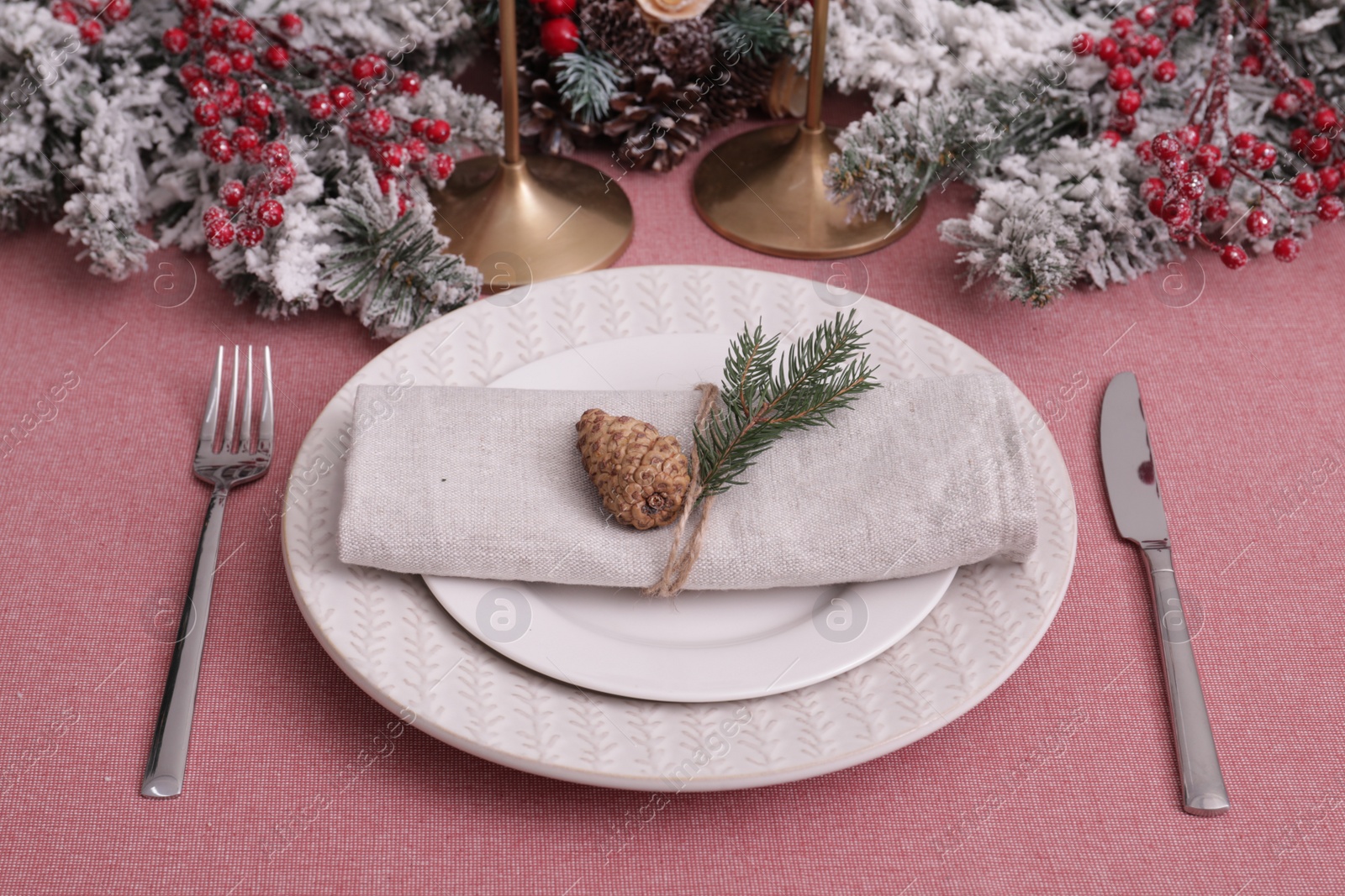 Photo of Festive place setting with beautiful dishware, cutlery and cone for Christmas dinner on pink tablecloth