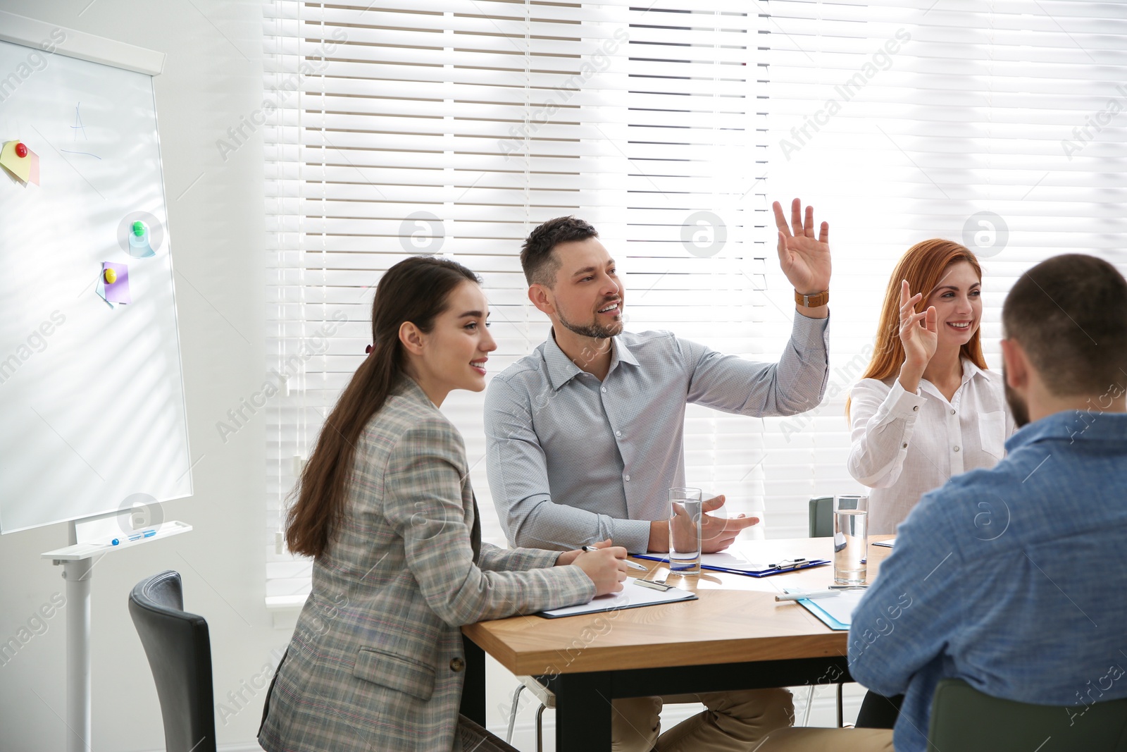 Photo of Man raising hand to ask question at business training in conference room