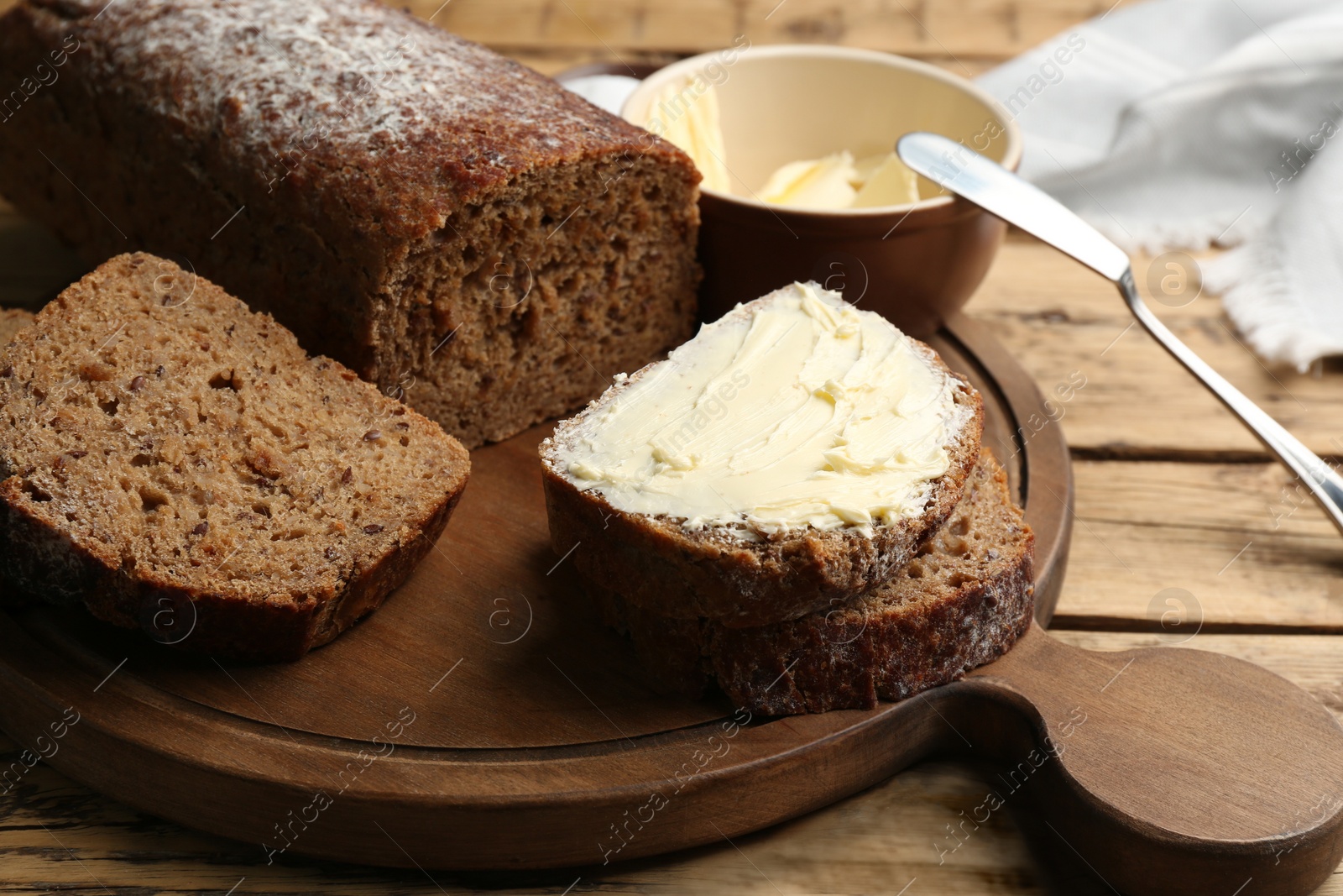 Photo of Tasty freshly baked bread with butter on wooden table