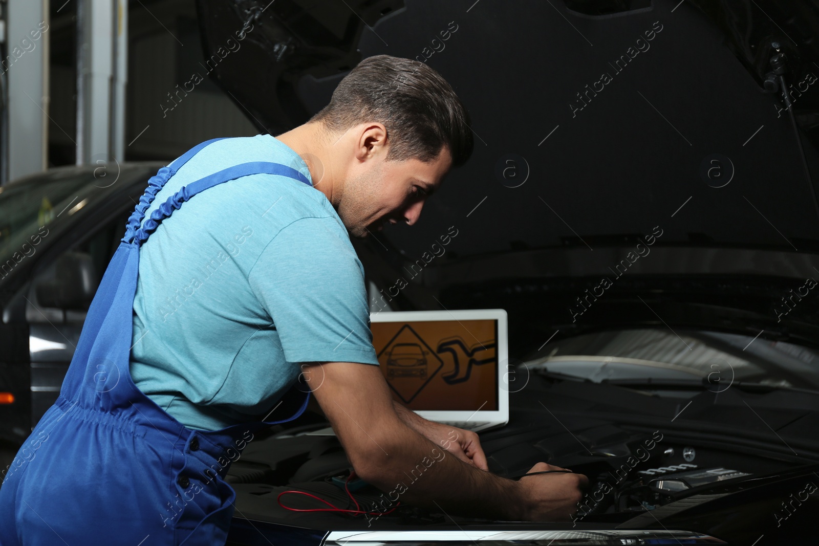 Photo of Mechanic with laptop doing car diagnostic at automobile repair shop