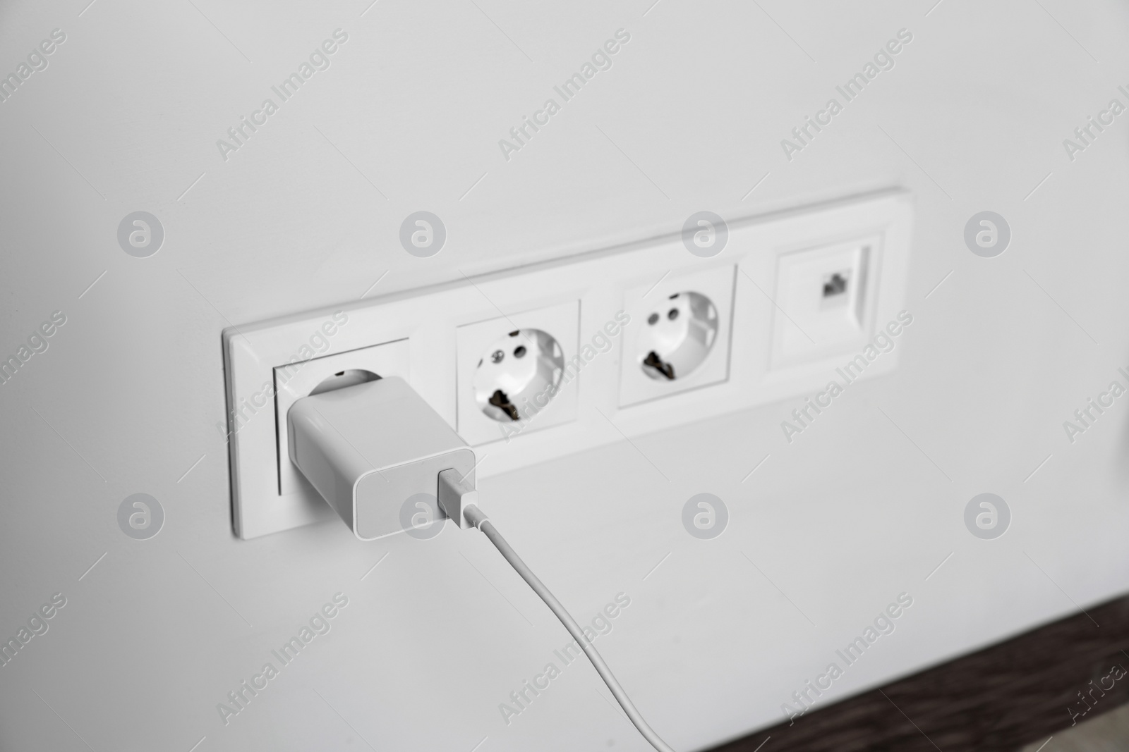 Photo of Charger adapter plugged in power socket indoors, space for text