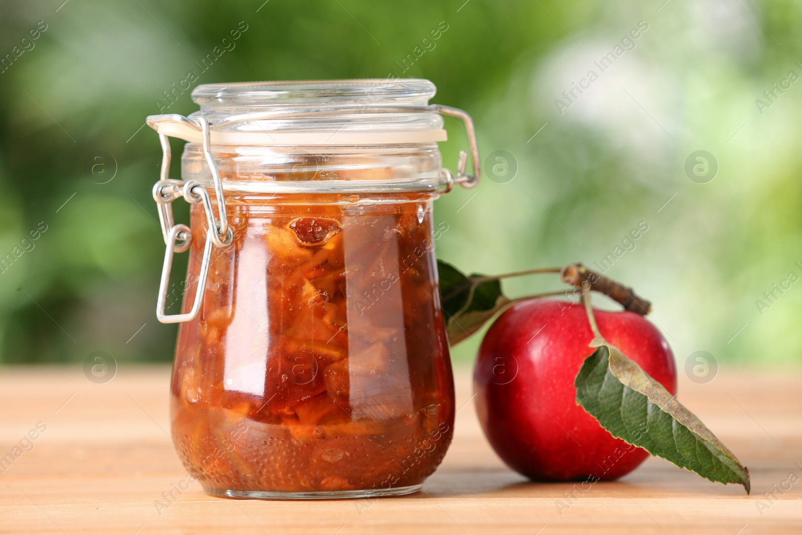 Photo of Delicious apple jam and fresh fruit on wooden table