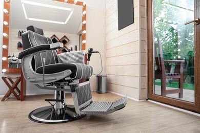 Photo of Stylish hairdresser's workplace with professional armchair in barbershop. Interior design