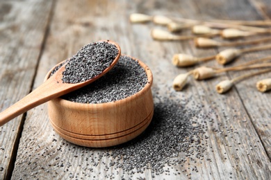 Photo of Bowl and spoon with poppy seeds on wooden table