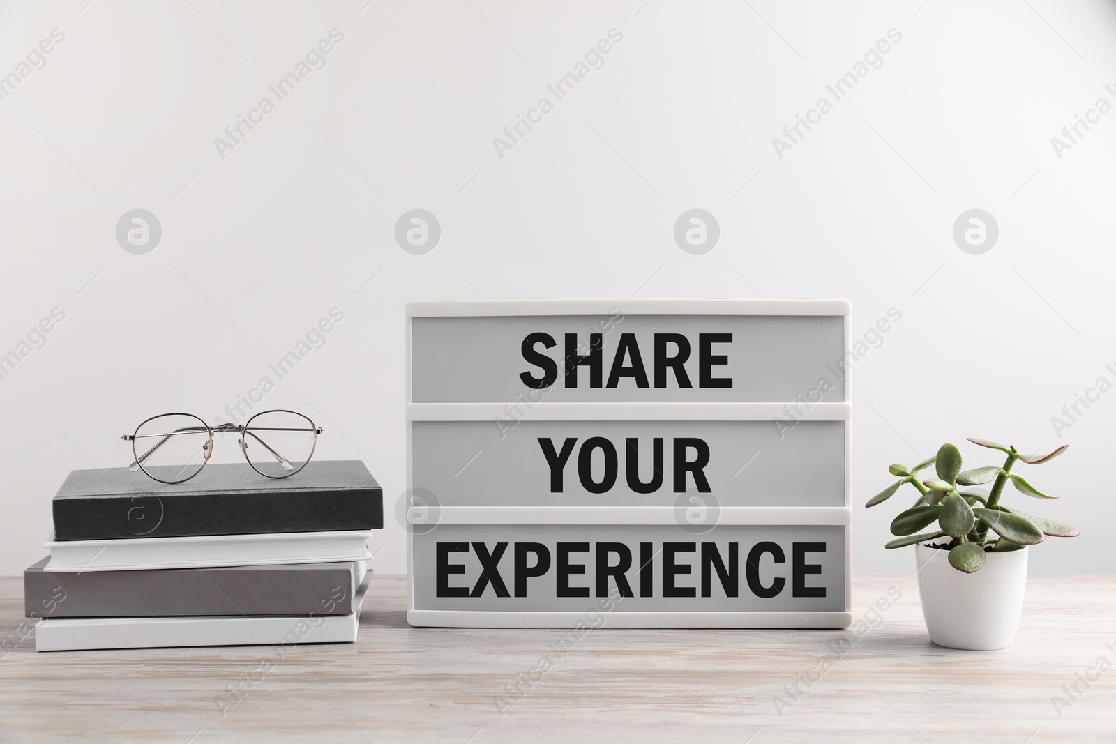 Image of Motivational phrase. Letter board with text Share Your Experience, books, glasses and houseplant on wooden table