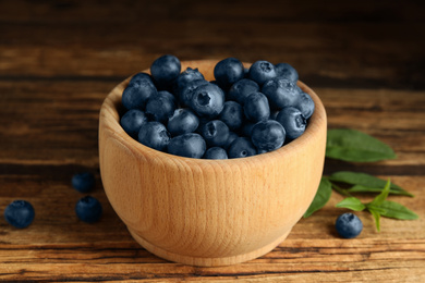 Photo of Fresh ripe blueberries in bowl on wooden table