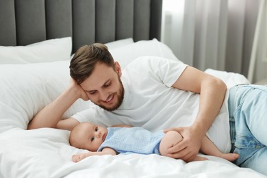 Father with his cute baby on bed indoors